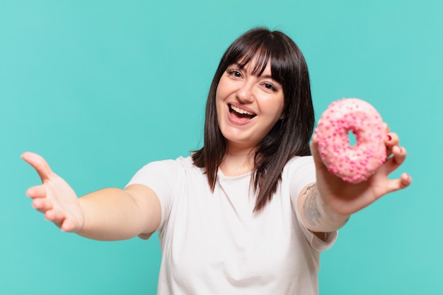 La giovane donna abbastanza formosa ha sorpreso l'espressione e tiene una ciambella