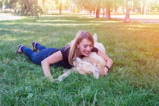 La giovane donna abbraccia il suo cane da riporto mentre si trova sull'erba