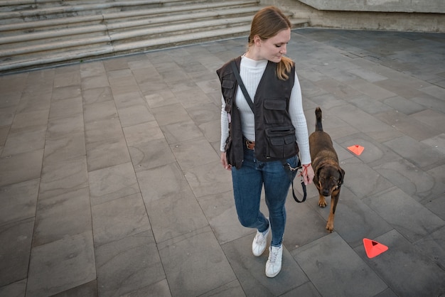 La giovane donna addestra il suo comportamento all'aperto del cane con giochi e ricompensa