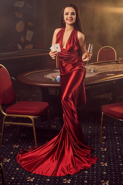 La giovane donna affascinante sta posando a un tavolo da poker nel casinò vip.