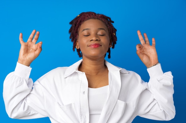 La giovane donna afro si rilassa con gli occhi chiusi contro la superficie blu