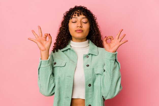 La giovane donna afroamericana afro isolata si rilassa dopo una dura giornata di lavoro, sta eseguendo yoga.