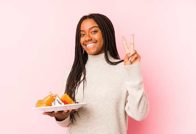 La giovane donna afroamericana che giudica un waffle ha isolato la mostra del numero due con le dita.