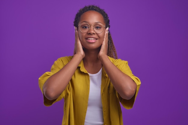 La giovane donna afroamericana copre le orecchie con le mani e sorride in studio