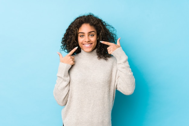 La giovane donna afroamericana dei capelli ricci sorride, indicando le dita alla bocca.