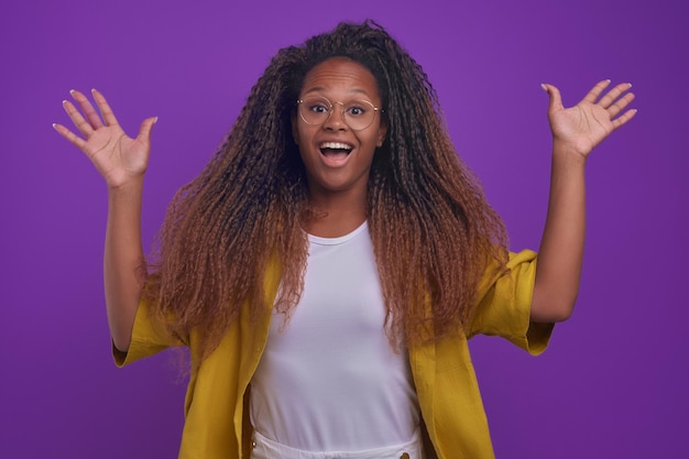 La giovane donna afroamericana felicissima con i capelli lunghi salta in piedi e agita le braccia