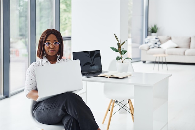 La giovane donna afroamericana in abiti formali è in ufficio con il laptop