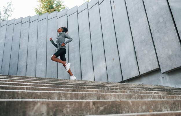 La giovane donna afroamericana in abiti sportivi si allena all'aperto durante il giorno