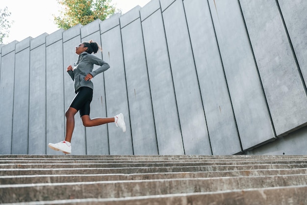 La giovane donna afroamericana in abiti sportivi si allena all'aperto durante il giorno