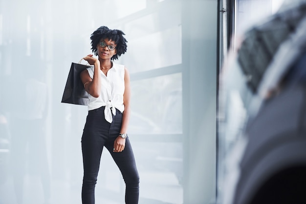 La giovane donna afroamericana in vetri sta all'interno con il pacchetto nelle mani.