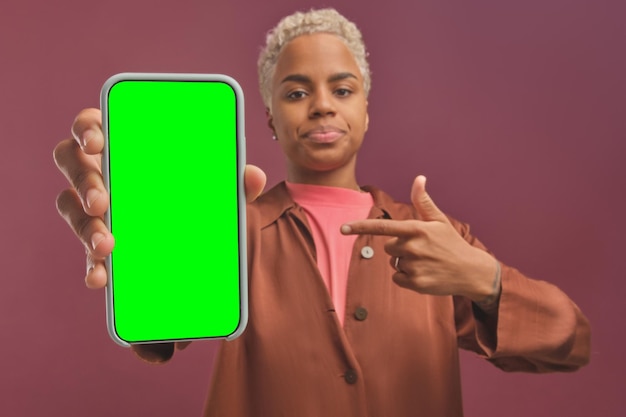 La giovane donna afroamericana indica con il dito il telefono con lo schermo verde