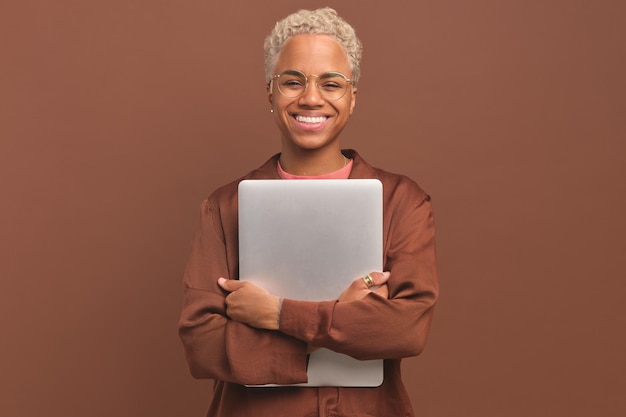 La giovane donna afroamericana positiva che stringe il laptop al petto si trova in studio