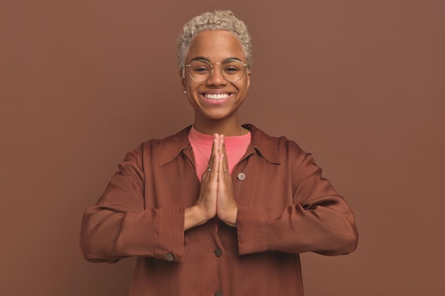La giovane donna afroamericana positiva fa il gesto di preghiera e guarda la macchina fotografica