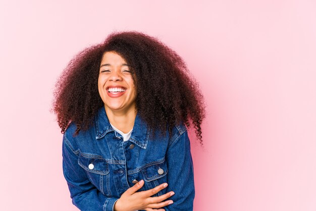 La giovane donna afroamericana ride felicemente e si diverte a tenere le mani sullo stomaco.