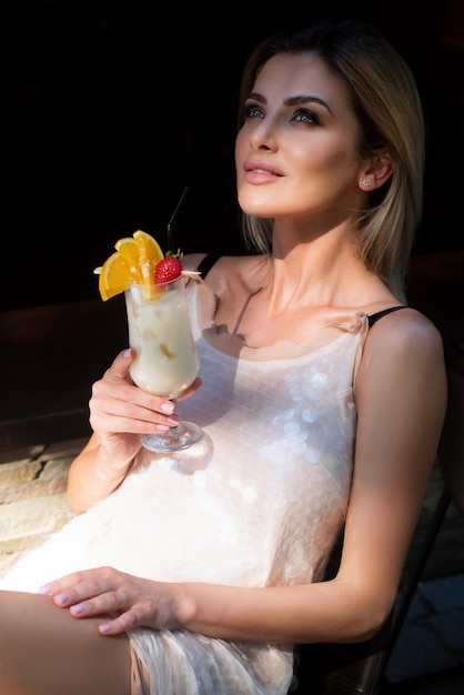 La giovane donna alla moda beve un cocktail al bar signora abbastanza moderna che tiene il bicchiere da cocktail attraente g