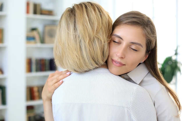 La giovane donna allegra sta abbracciando sua madre di mezza età nel soggiorno.