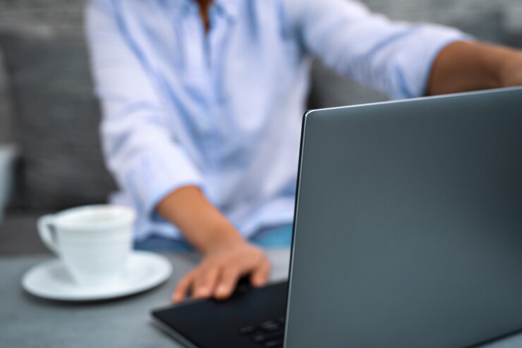 Foto la giovane donna apre il coperchio di un laptop per lavorare a distanza da casa.