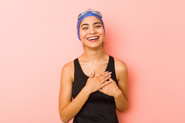 La giovane donna araba del nuotatore ha isolato la risata mantenendo le mani sul cuore, concetto di felicità.