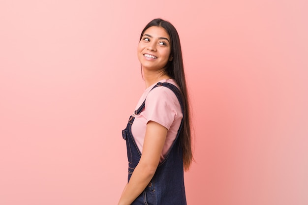 La giovane donna araba graziosa che indossa un denim dei jeans sembra da parte sorridere, allegro e piacevole.