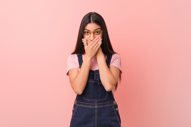 La giovane donna araba graziosa che indossa un denim ha colpito la bocca della copertura colpita con le mani.