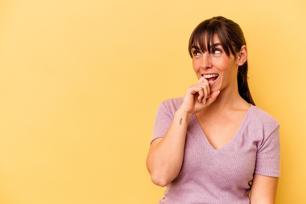 La giovane donna argentina isolata su fondo giallo si è rilassata pensando a qualcosa guardando uno spazio di copia.