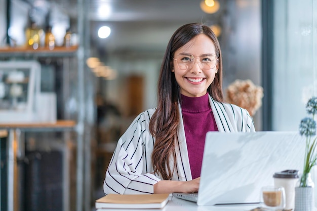 La giovane donna asiatica attraente indossa il panno casual usa la mano lo smartphone e il dispositivo portatile comunica il contatto sociale nel ristorante del bar sedersi al bancone accanto alla luce del giorno della grande finestra