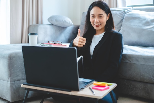 La giovane donna asiatica che lavora come freelance lavora sul computer portatile a casa lavorando dal concetto di casa