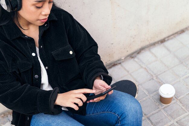 La giovane donna asiatica con le cuffie si diverte ad ascoltare la musica con il suo telefono cellulare