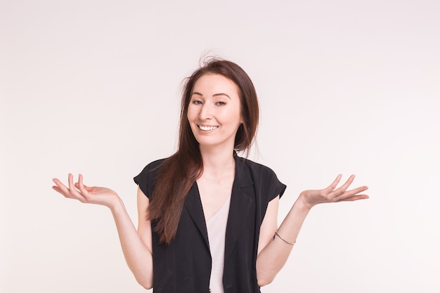 La giovane donna asiatica del brunette sta scrollando le spalle su bianco.