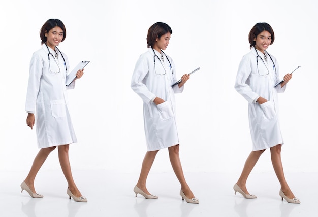 La giovane donna asiatica del medico di lunghezza intera 20s indossa il cappotto uniforme dello stetoscopio che cammina in avanti a destra