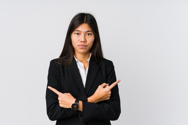 La giovane donna asiatica di affari punta lateralmente, sta cercando di scegliere tra due opzioni.