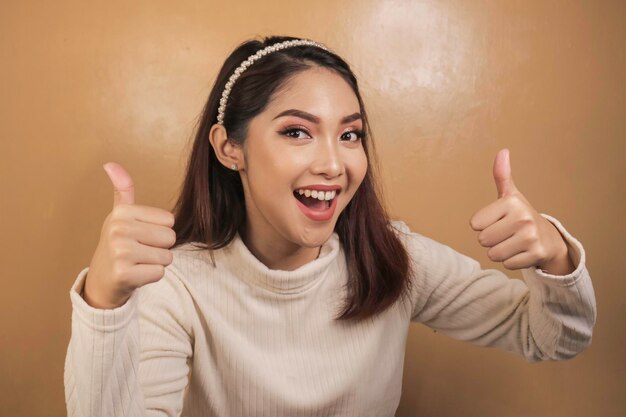 La giovane donna asiatica è selfie con la faccia sorridente felice e il segno giusto vicino alla bocca guarda la telecamera