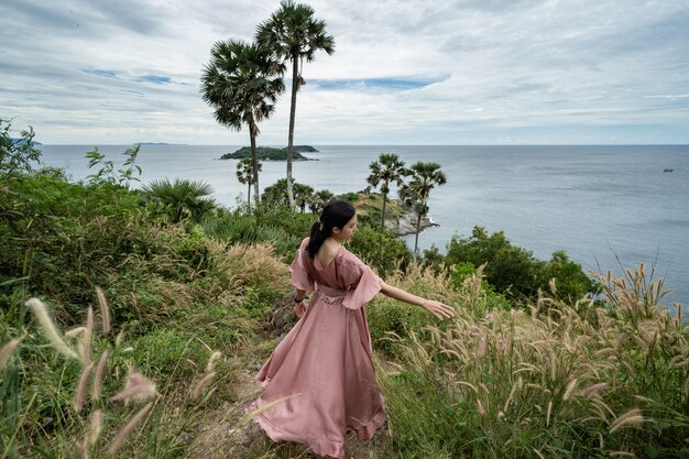 La giovane donna asiatica in vestito rosa gode e si rilassa al punto di vista del punto di riferimento del capo di Promthep a Phuket