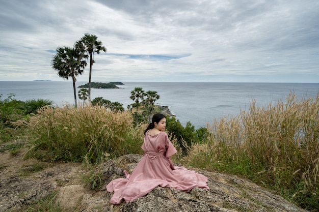 La giovane donna asiatica in vestito rosa gode e si rilassa al punto di vista del punto di riferimento del capo di Promthep a Phuket