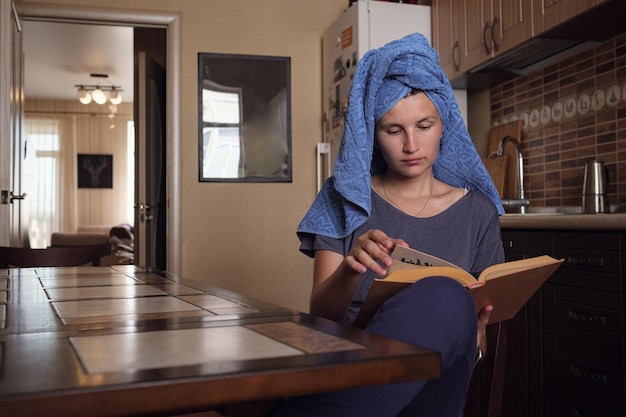 La giovane donna asiatica legge un libro in cucina