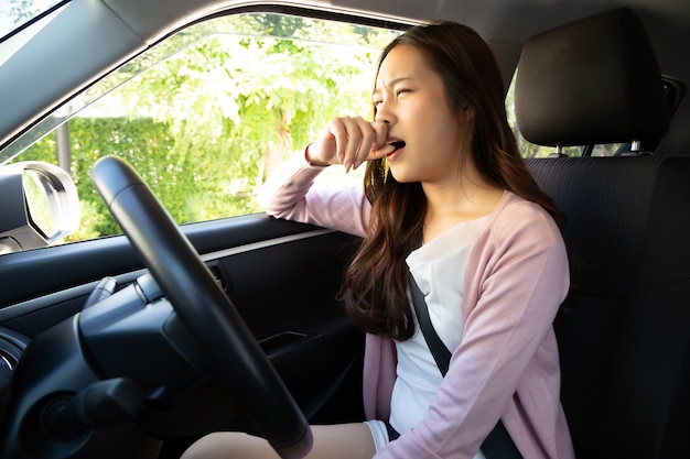 La giovane donna asiatica si tiene il naso a causa del cattivo odore sporco in auto