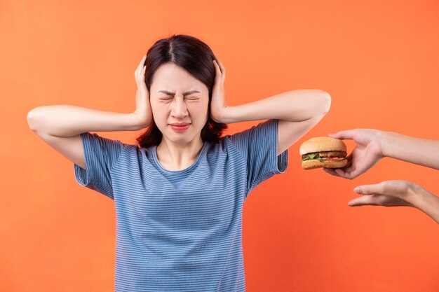 La giovane donna asiatica sta cercando di rinunciare all'abitudine di mangiare hamburger