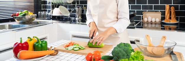 La giovane donna asiatica sta preparando insalata di verdure dell'alimento sano