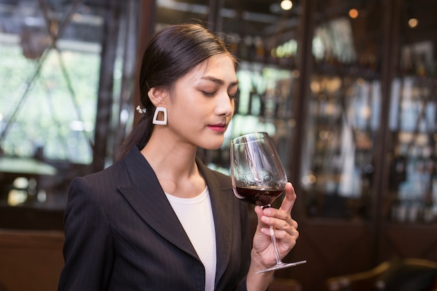 La giovane donna asiatica sta tenendo il bicchiere di vino e l&#39;odore