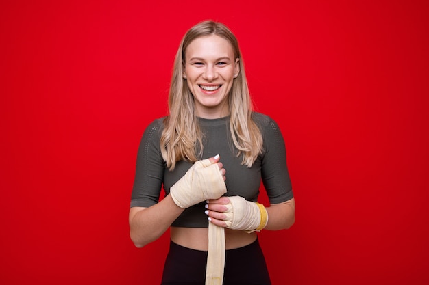 La giovane donna atletica si fascia le mani prima dell'allenamento di boxe