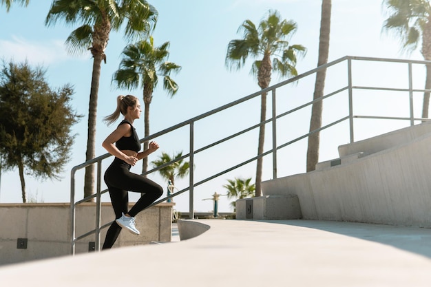 La giovane donna atletica sta correndo su scale di cemento durante il suo allenamento estivo in strada