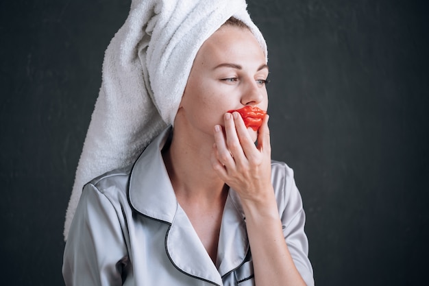 La giovane donna attacca una maschera cosmetica sulle labbra.