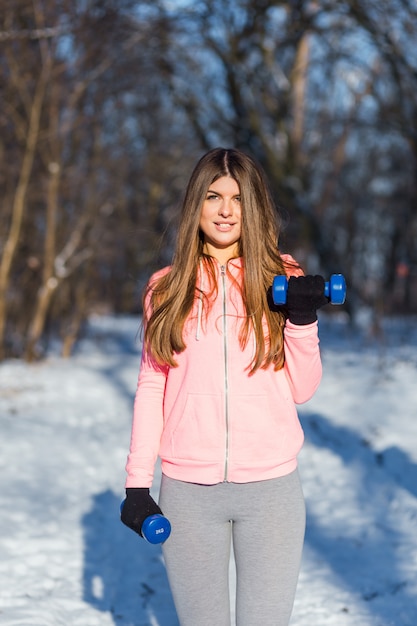 La giovane donna attiva esegue un esercizio con i dumbbells