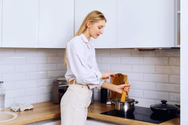 La giovane donna attiva mette gli spaghetti in acqua bollente