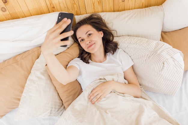 La giovane donna attraente si fa un selfie subito dopo essersi svegliata