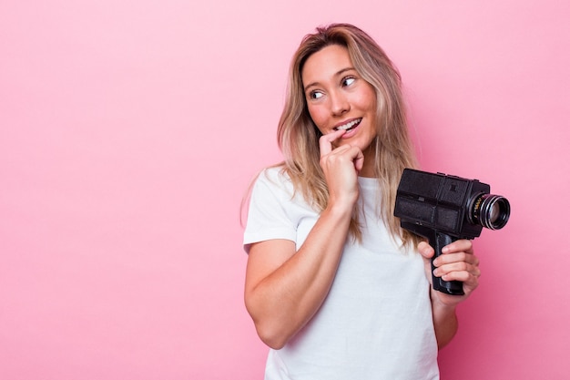 La giovane donna australiana che filma con una videocamera vintage ha isolato il pensiero rilassato su qualcosa che guarda uno spazio di copia.