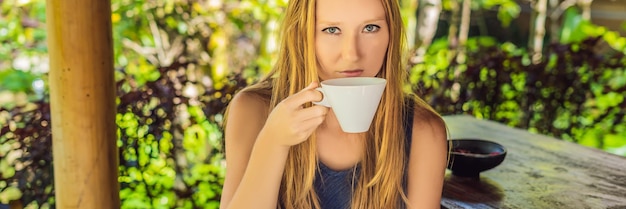 La giovane donna beve il caffè Luwak nel gazebo BANNER, formato lungo