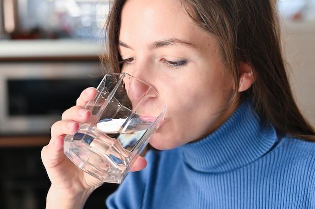 La giovane donna beve l'acqua da un bicchiere