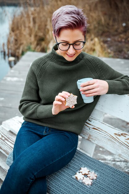 La giovane donna beve la tazza di caffè sulla riva del lago