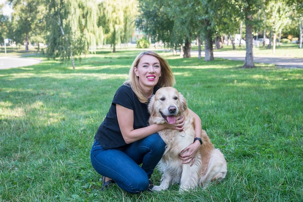 La giovane donna bionda abbraccia il suo cane. Documentalista di razza di cane con una ragazza nel parco.